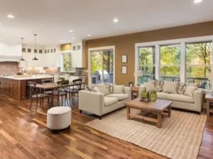 An open-concept living room and kitchen area with hardwood floors and large windows