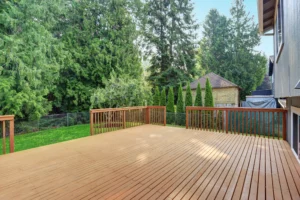 Empty walkout deck boasts redwood railings overlooking well kept back yard
