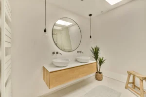 a bathroom with two sinks and a mirror on the wall next to it is a plant in a wooden stool